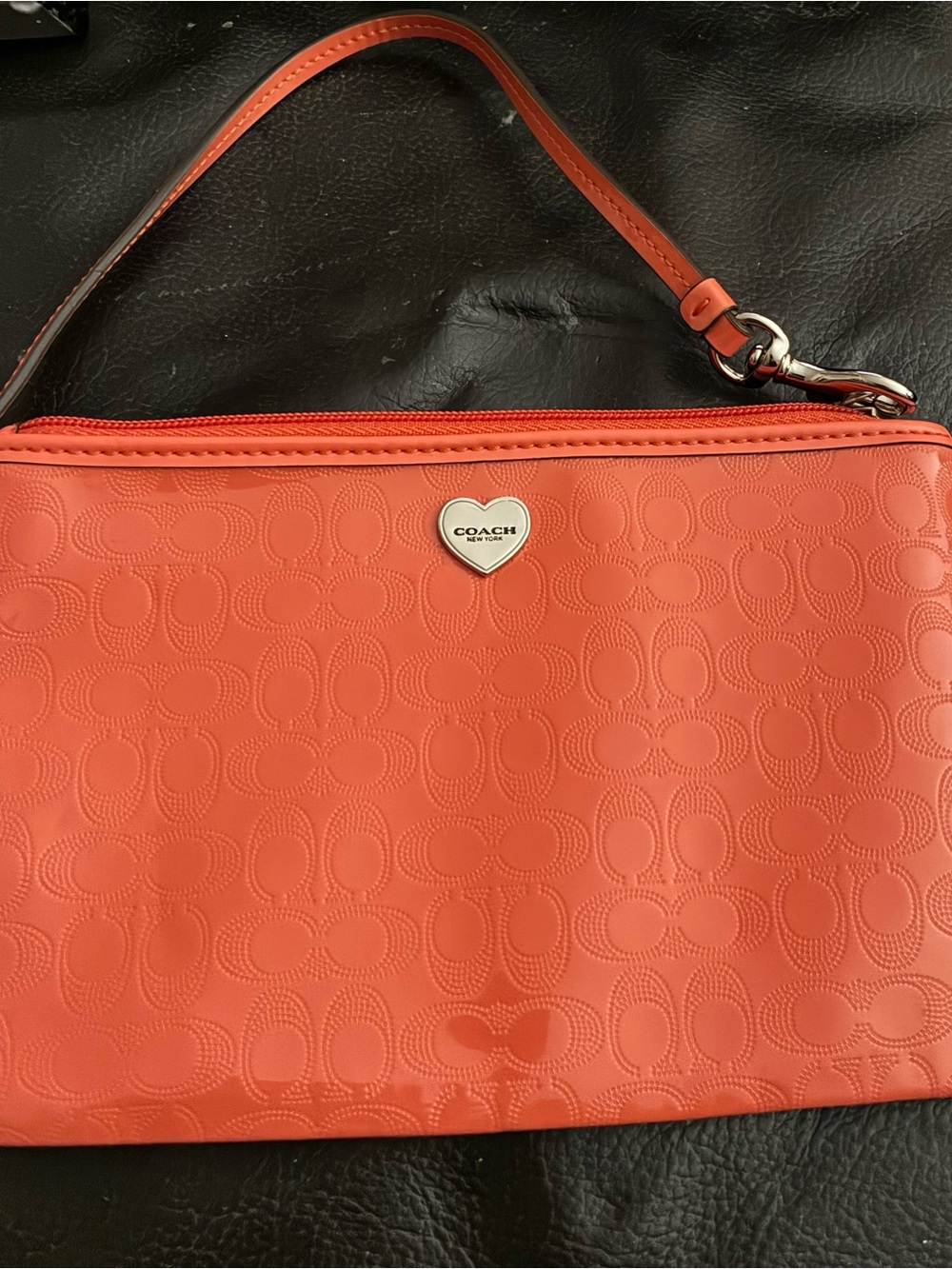 Coach orange patent leather wristlet with a silver heart emblem